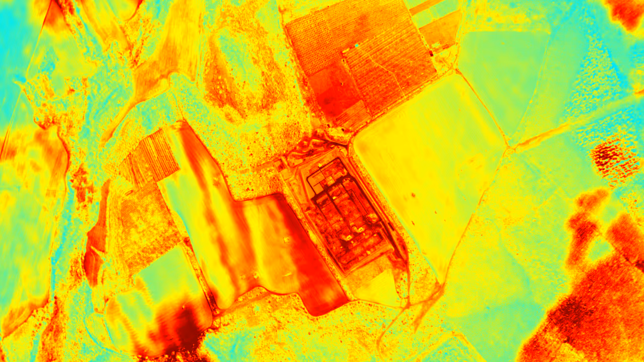 Thermal image showing varied heat levels across agricultural fields and a central industrial facility.